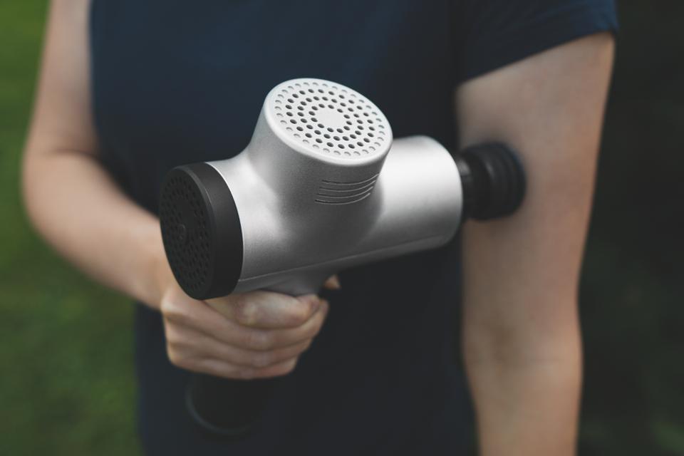 Woman massaging his hand with massage percussion device after workout.