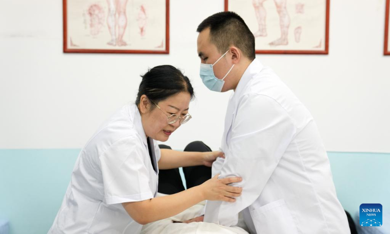 Zhang Lin (L) instructs a visually impaired student on massage techniques at Beijing Union University in Beijing, capital of China, Sept. 8, 2022. (Xinhua/Ju Huanzong)