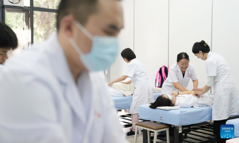 Zhang Lin (2nd R) instructs a visually impaired student on massage techniques at Beijing Union University in Beijing, capital of China, Sept. 8, 2022. (Xinhua/Ju Huanzong)