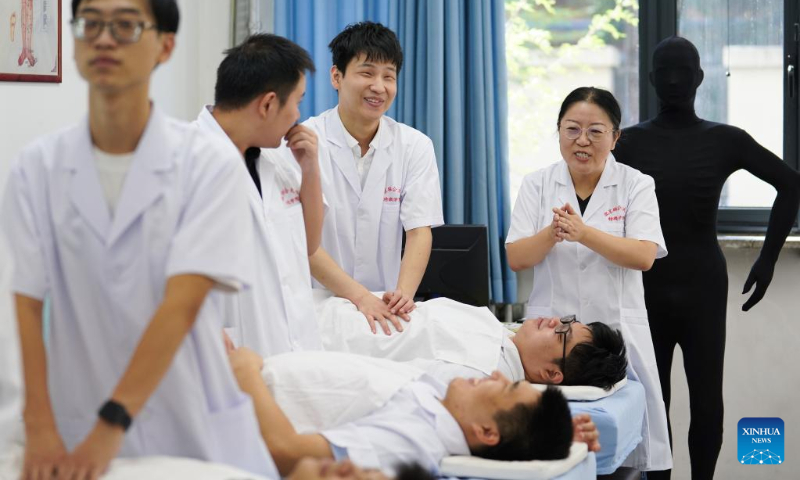 Zhang Lin (1st R) instructs visually impaired students on massage techniques at Beijing Union University in Beijing, capital of China, Sept. 8, 2022. (Xinhua/Ju Huanzong)